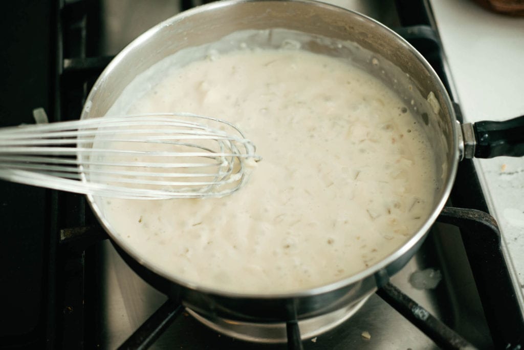 whisking the laughing cow cheese sauce in a sauce pan