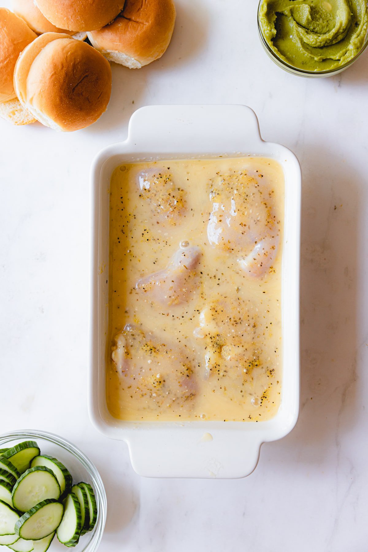 Italian dressing poured over chicken thighs in a shallow dish. 