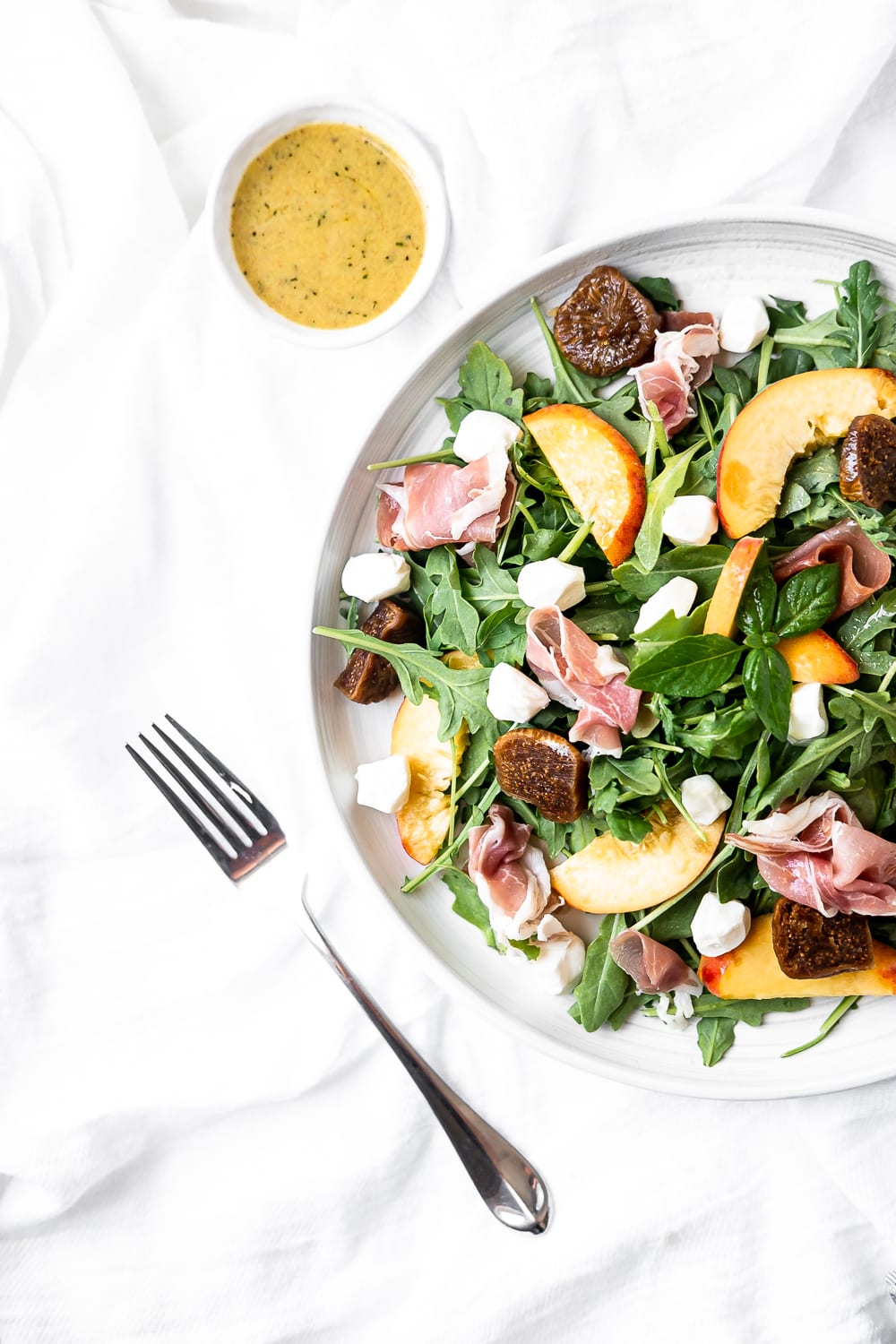 prosciutto and peach salad on white background with fork