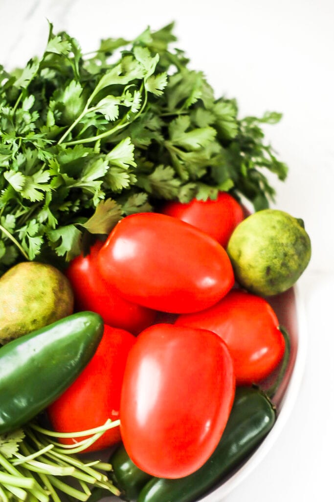 close up of tomatoes, lime, jalapeño, and cilantro