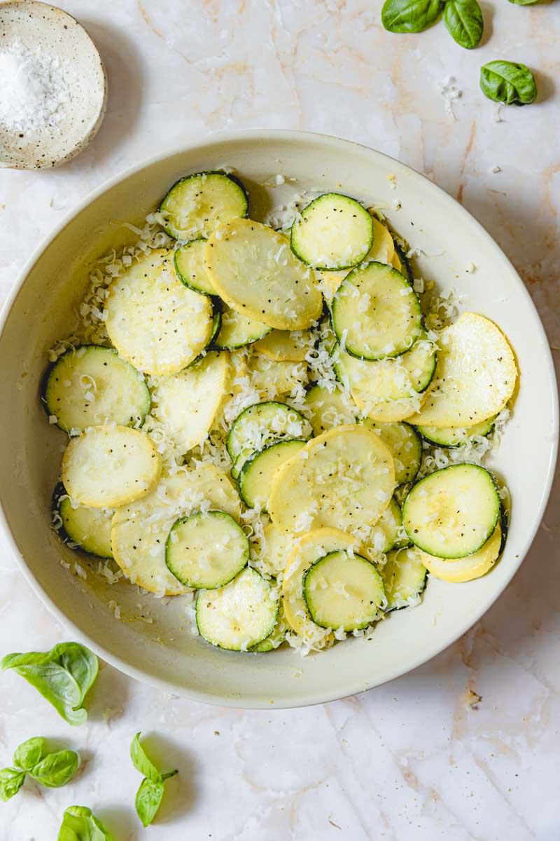 Squash, parmesan, and lemon pepper seasoning mixed together in a bowl.