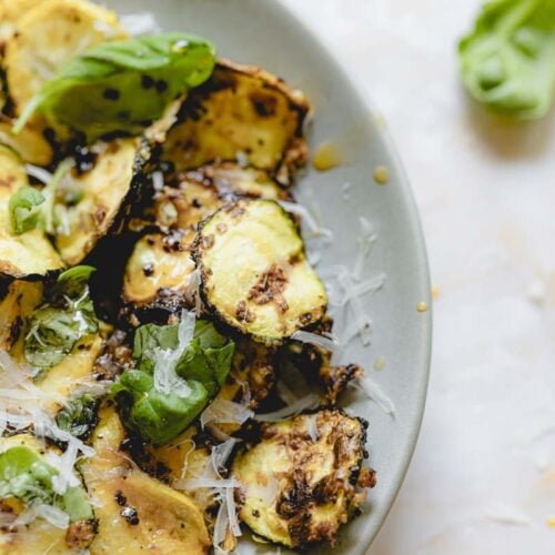 Air fryer squash in a bowl garnished with basil and parmesan cheese.