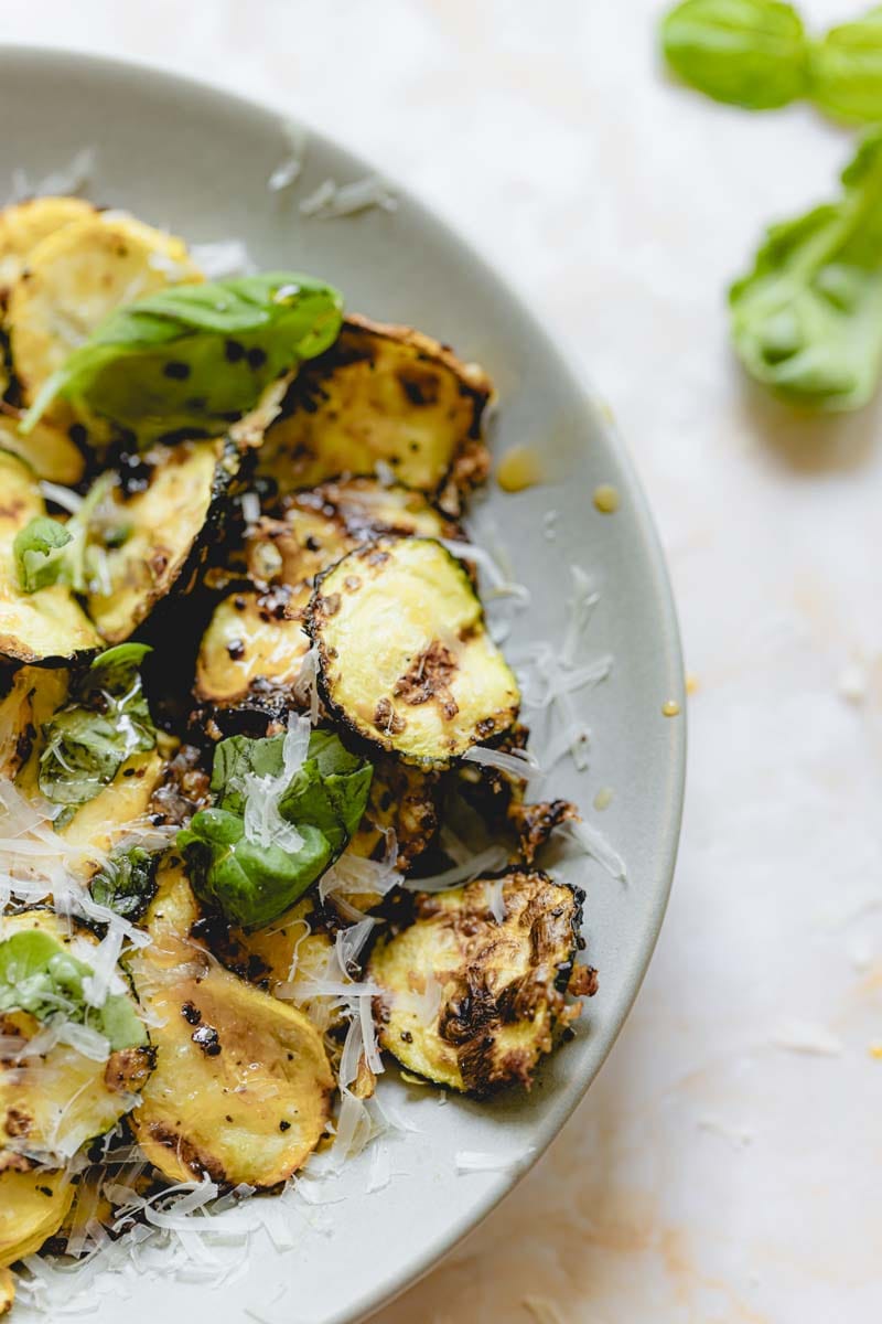 Air fryer squash in a bowl garnished with basil and parmesan cheese. 