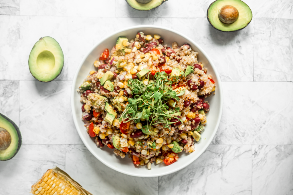 bowl of quinoa and corn salad surrounded by avocados 