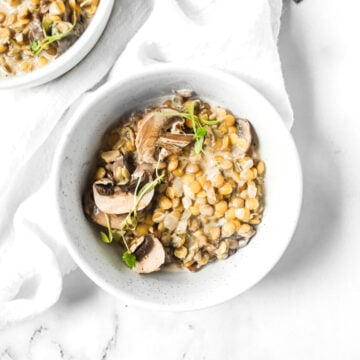 white bowl with mushroom lentil risotto garnished with mushrooms