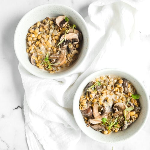 lentil risotto with mushroom and sage in 2 bowls with a white linen around them