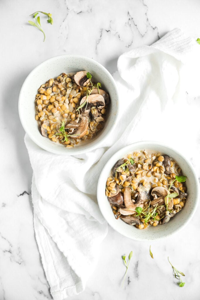 lentil risotto with mushroom and sage in 2 bowls with a white linen around them