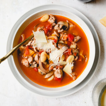 bowl of chicken cacciatore soup topped with parmesan with a spoon