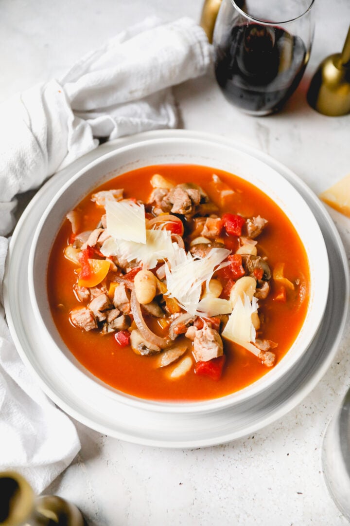 chicken cacciatore soup in a white bowl and white linen towel next to it. 