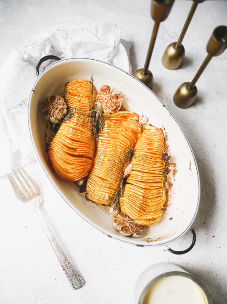 3 hasselback squash in a white roasting pan
