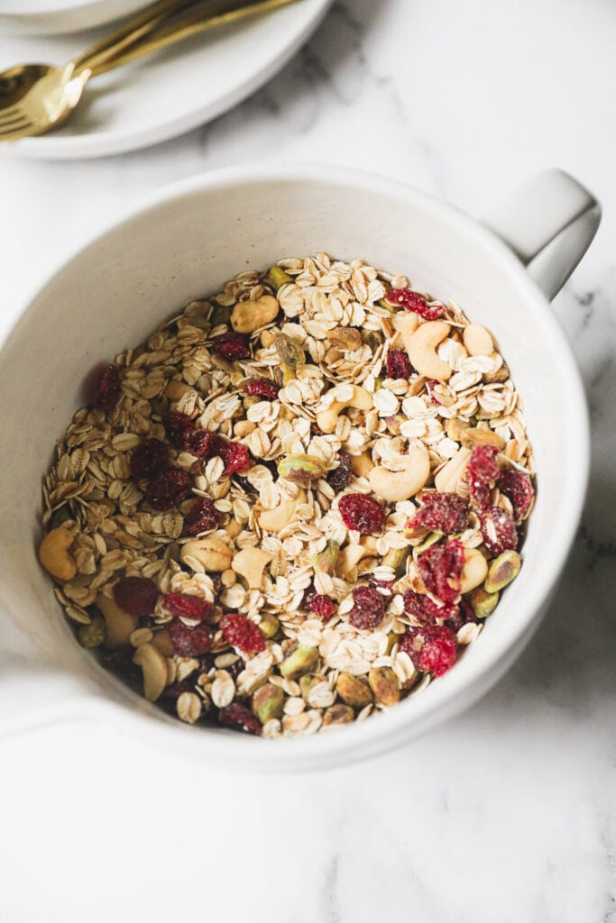 granola being mixed in a white bowl 