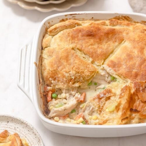 white baking dish of turkey pot pie with a slice cut out of it.