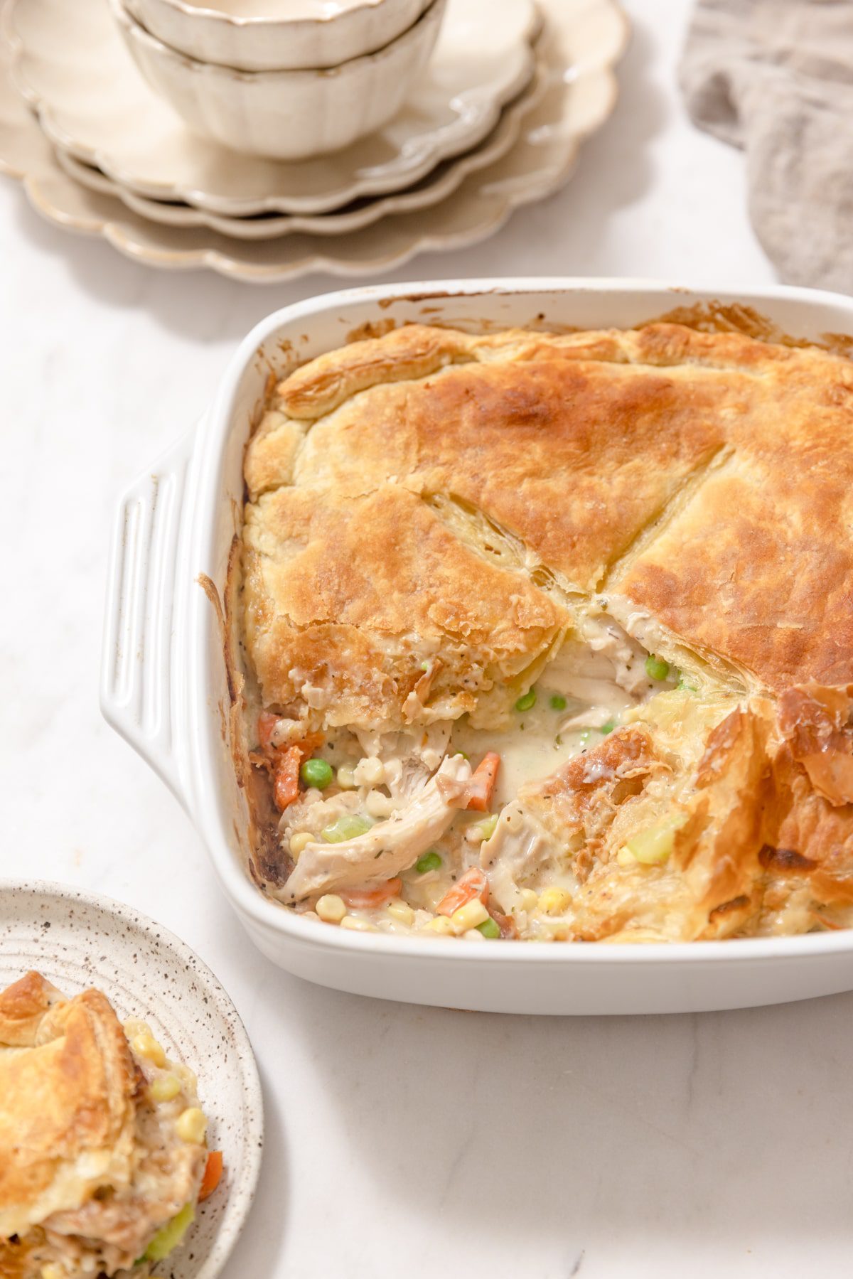 white baking dish of turkey pot pie with a slice cut out of it. 