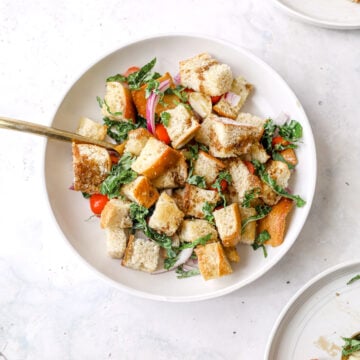 panzanella salad in a white bowl with gold fork