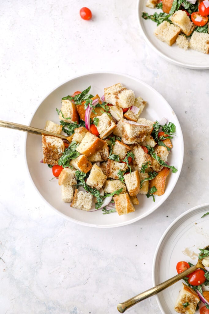 panzanella salad in a white bowl with gold fork