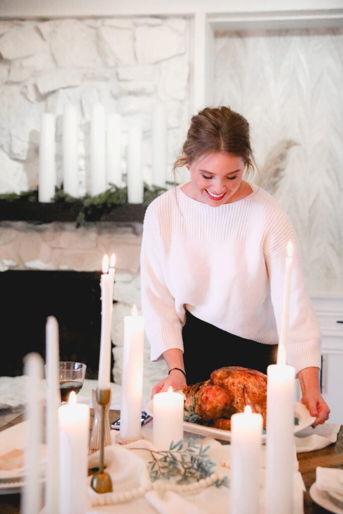 Sara sitting down a turkey on a set thanksgiving table 