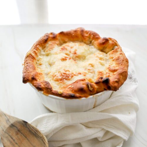 French Onion Pot Pie with white linen and wooden spoon