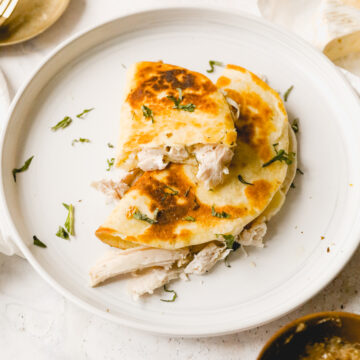 leftover turkey quesadillas on a white plate with Italian herb garnish