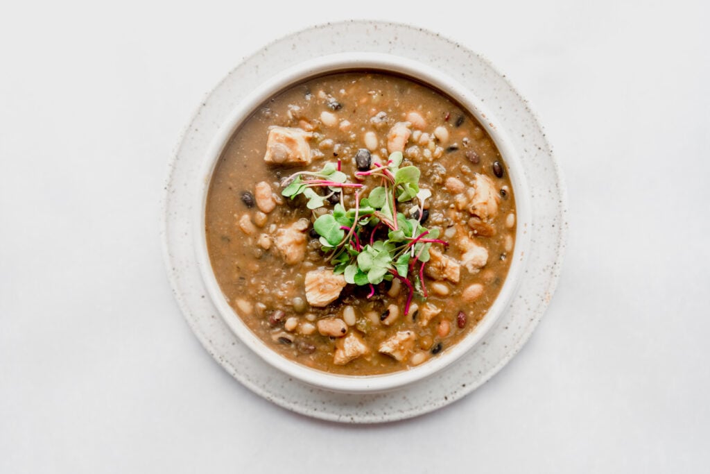 bowl of 15 bean chili with micro greens as a garnish 
