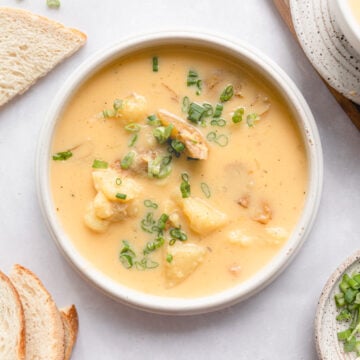 homemade potato soup in a white bowl surrounded by sourdough toast