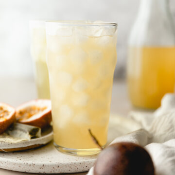 Panera green tea in a glass surrounded by passionfruit