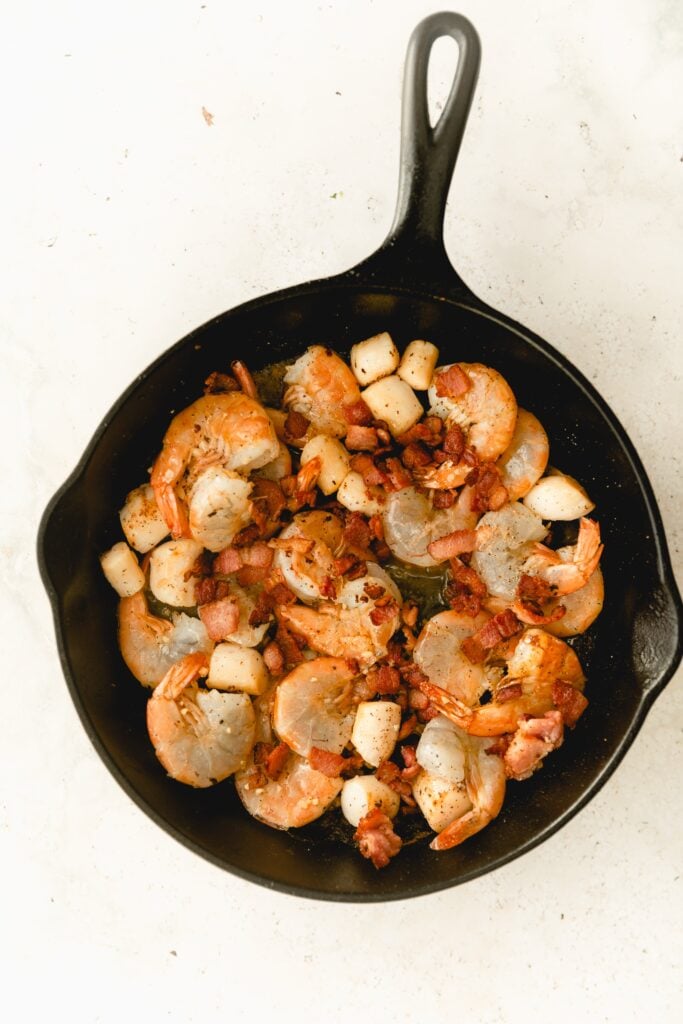 shrimp, scallops, and bacon in a cast iron pan