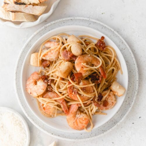 shrimp scallop pasta on white dishes served with bread