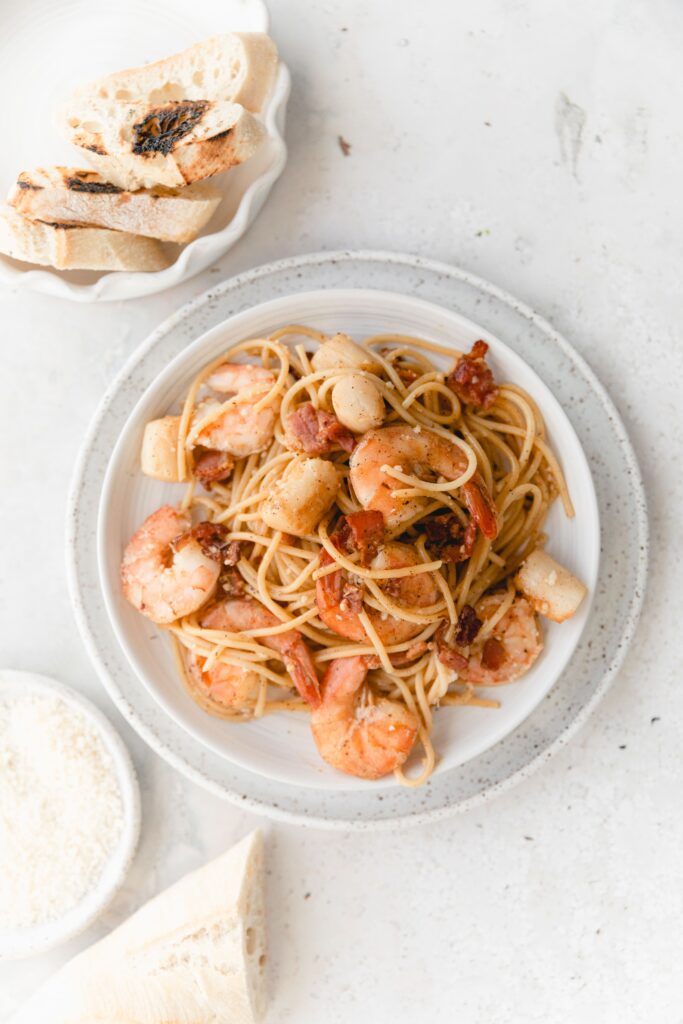 shrimp scallop pasta on white dishes served with bread