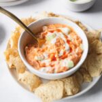 buffalo jackfruit dip in a white bowl surrounded by chips
