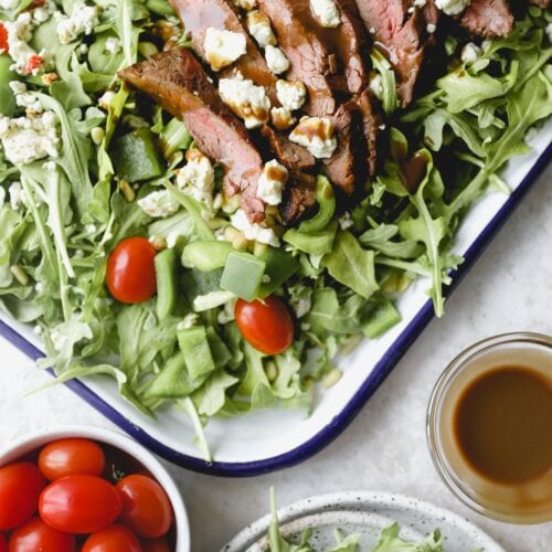 close up of flank steak on a bed of arugula lettuce