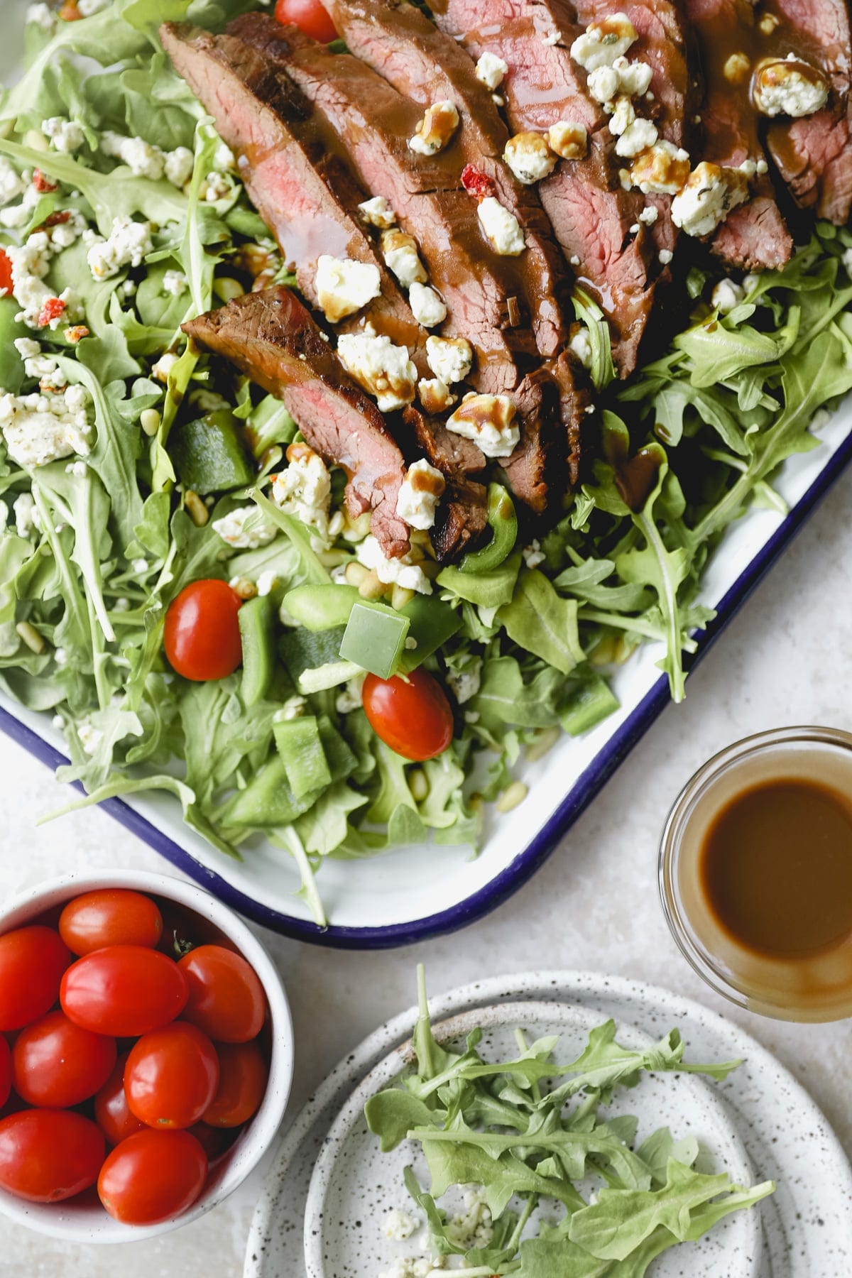 close up of sliced flank steak with balsamic drizzle over arugula salad
