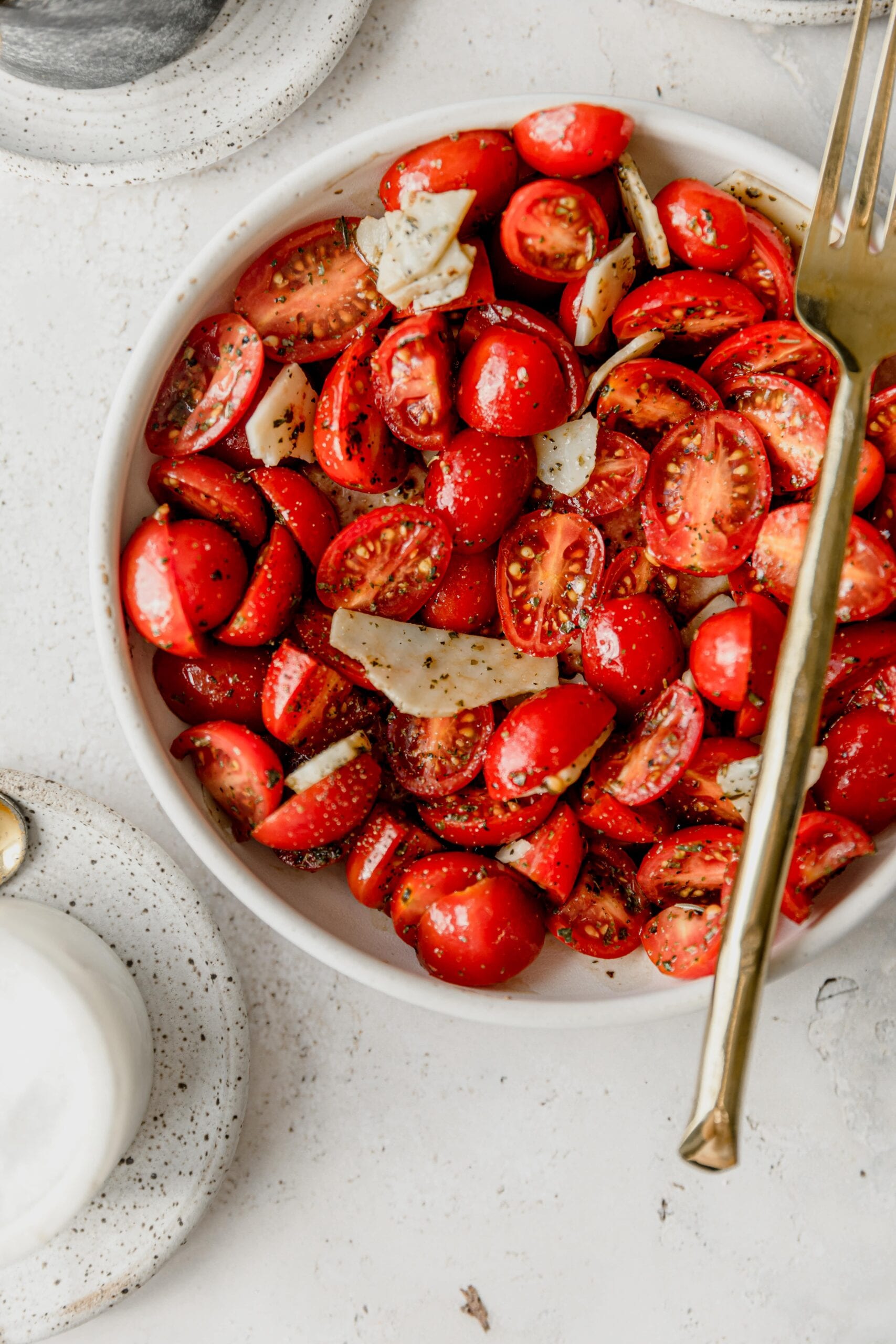 white bowl full of cherry tomatoes in Italian marinade with a gold fork