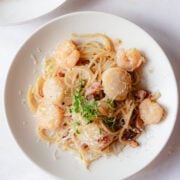 Final plated shrimp scallop pasta garnished with micro greens.