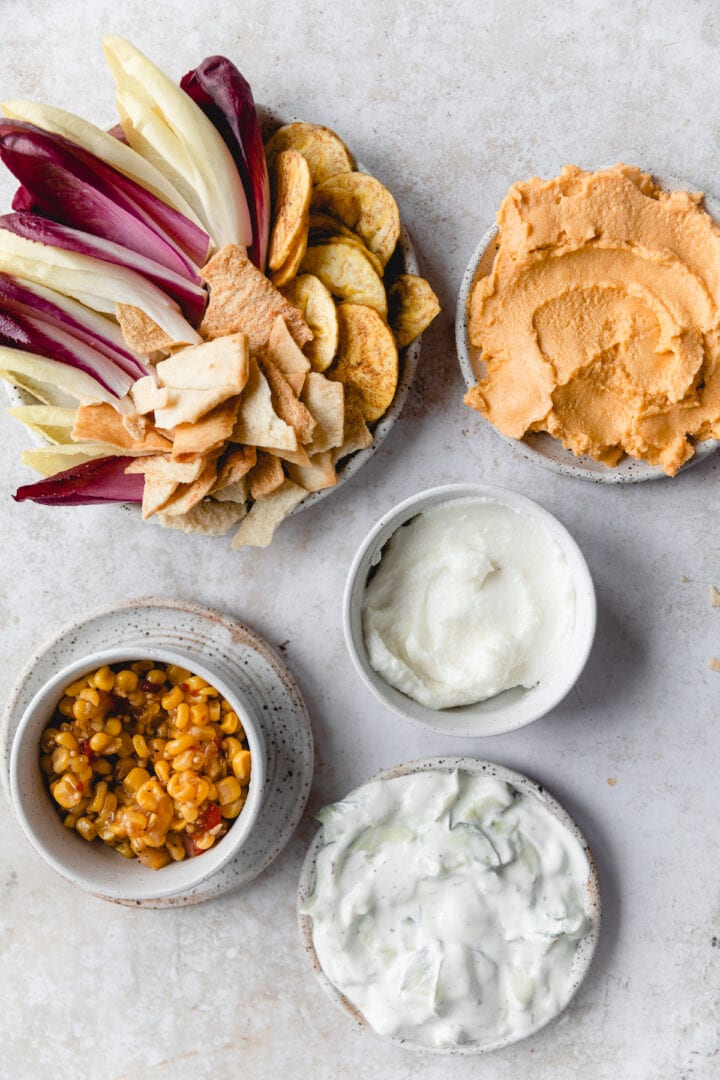 bowls of dip (queso, garlic sauce, corn dip, and tzatziki)
 and chips
