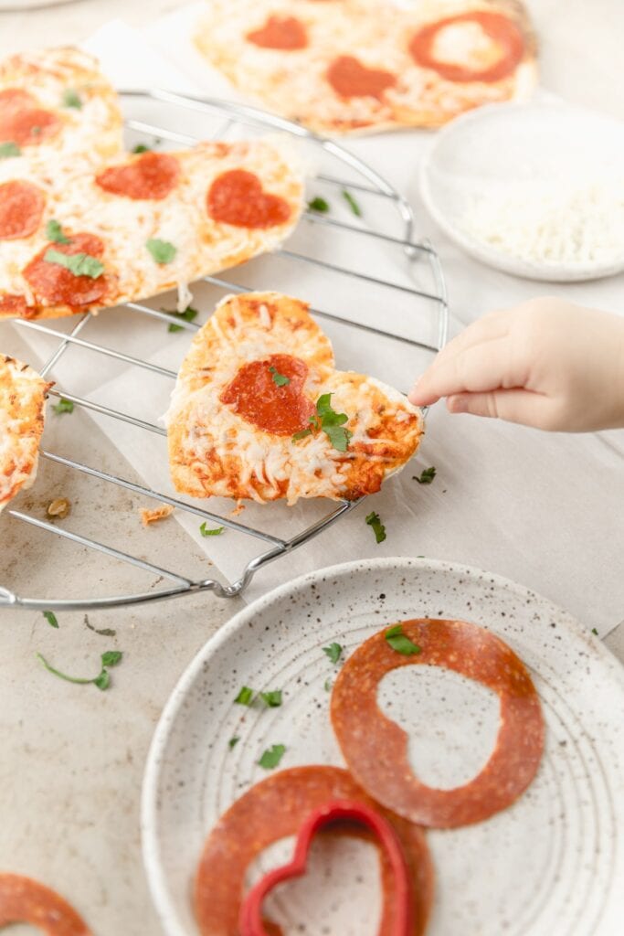 child's hand reaching for tortilla pizza 
