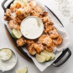skillet lined with parchment with coconut shrimp and coconut dipping sauce