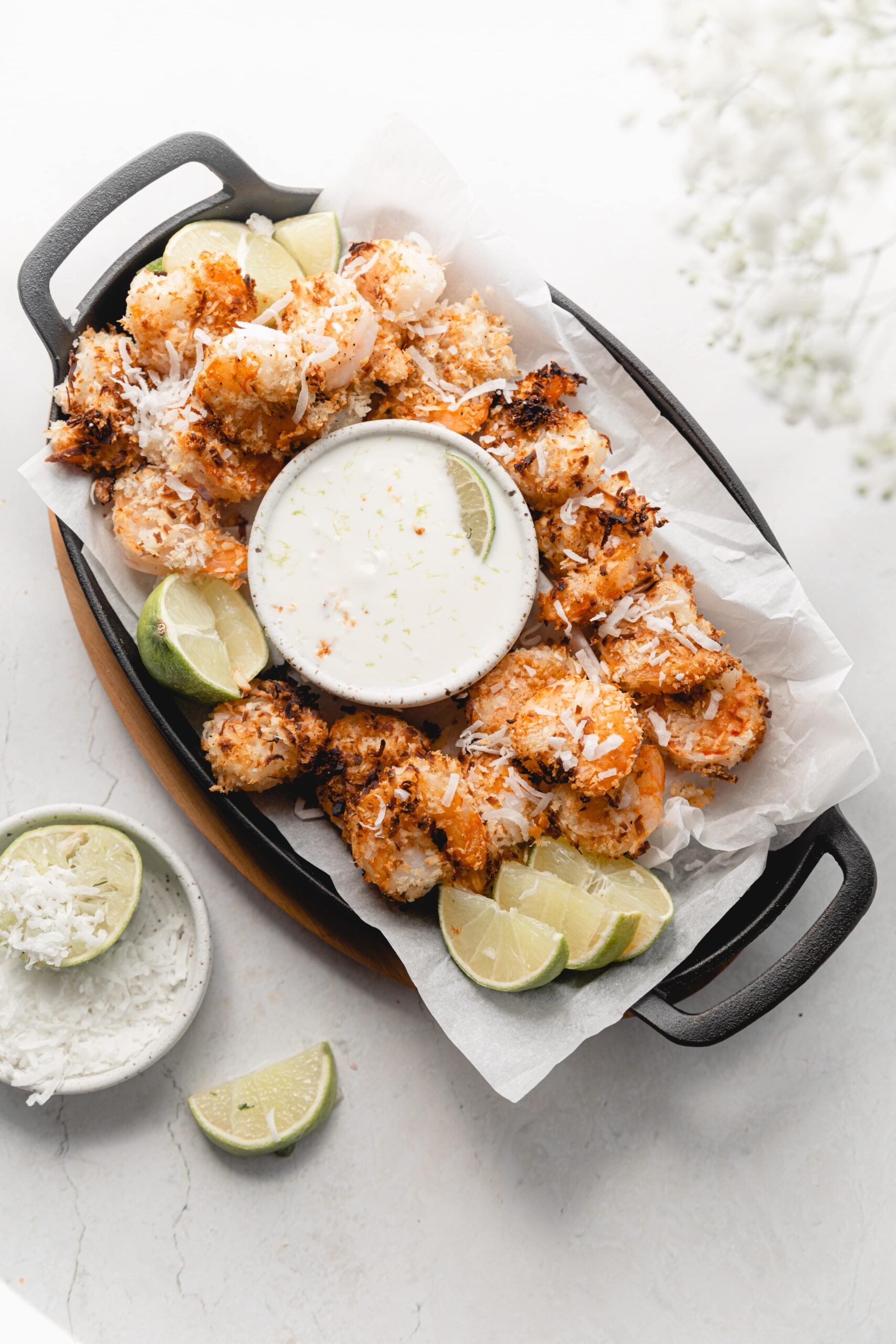 skillet lined with parchment with coconut shrimp and coconut dipping sauce