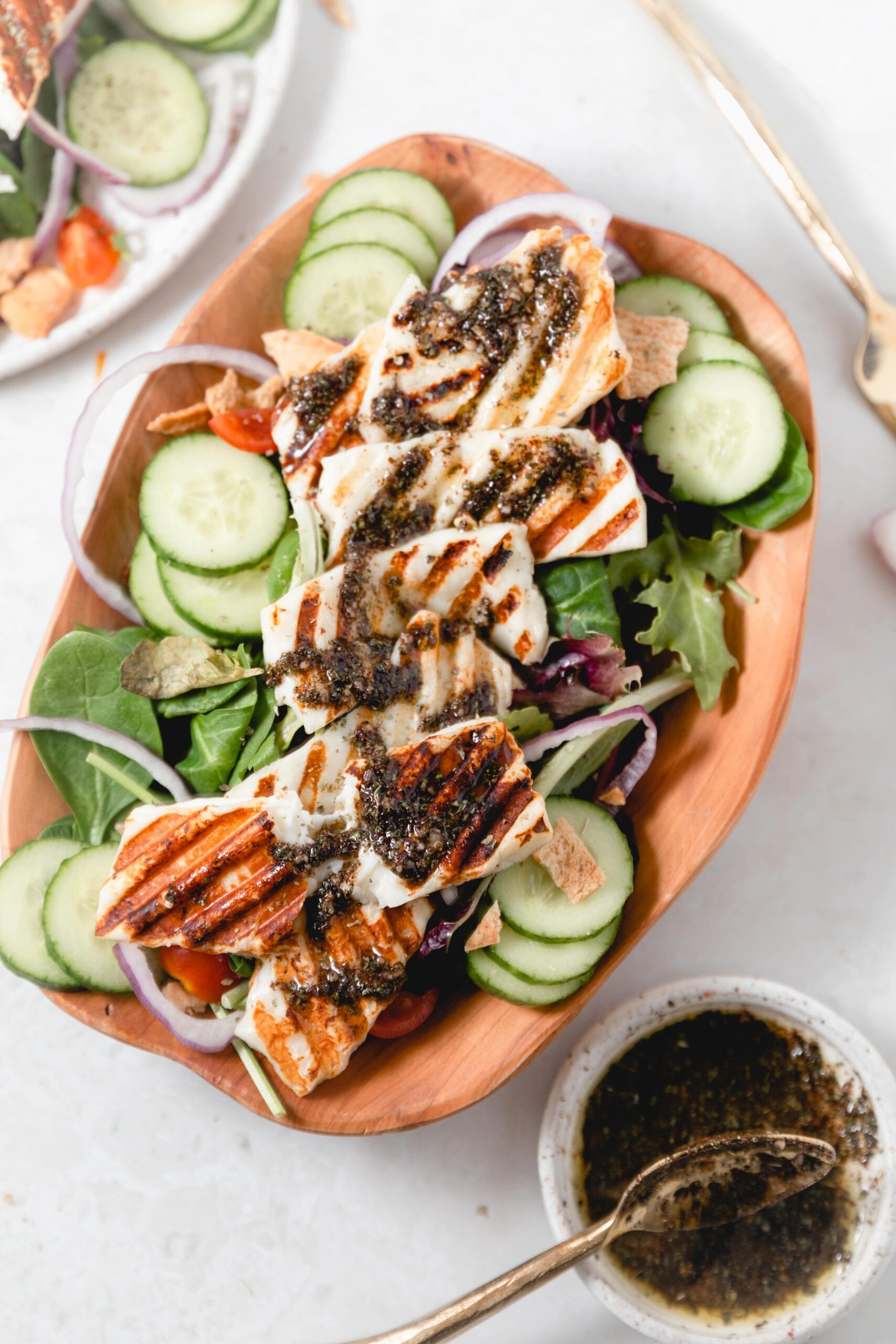 wooden bowl with grilled Halloumi Salad topped with dressing 