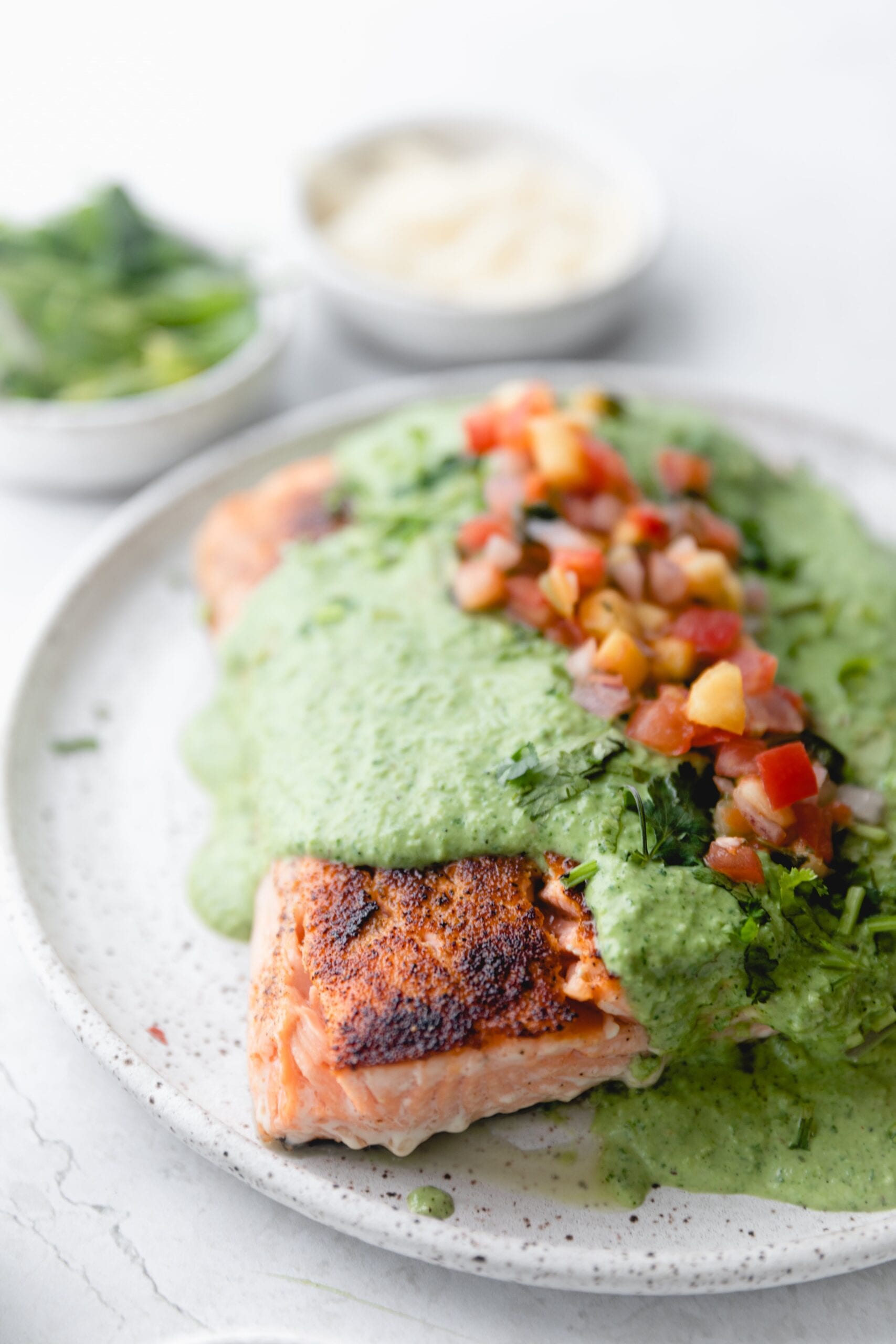 plate of salmon covered in poblano sauce and topped with pico. 