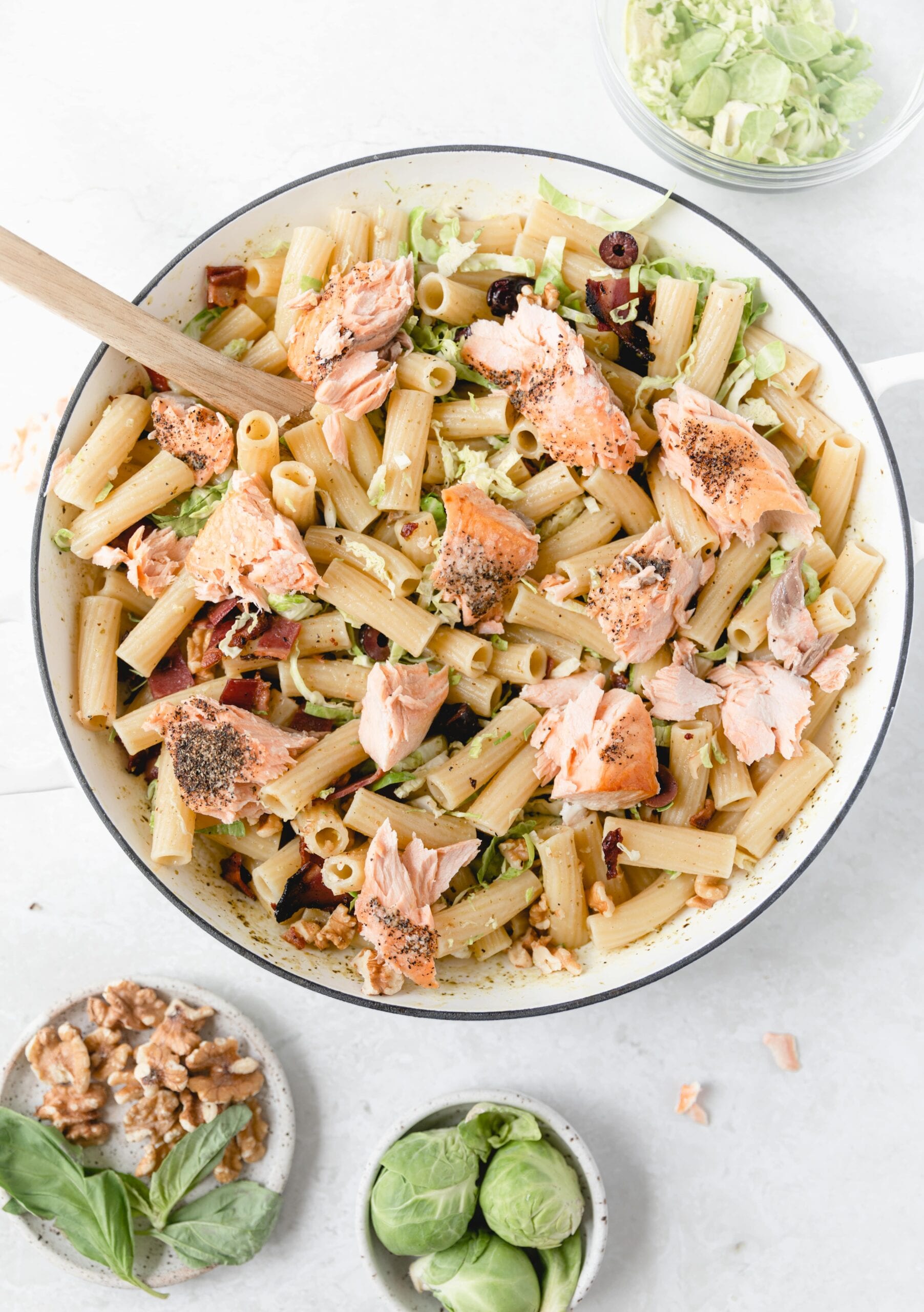 white skillet with pesto pasta topped with salmon