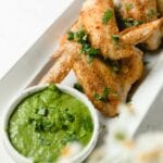 White plate with wings and side sauce of Chimichurri