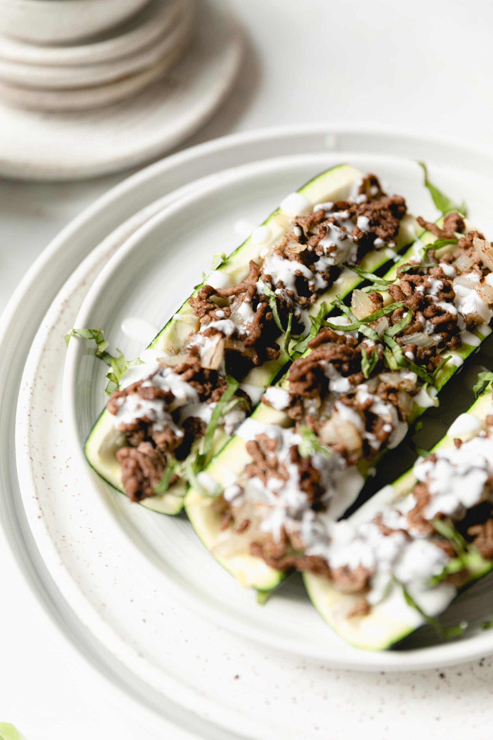 beef stuffed courgettes on a white plate
