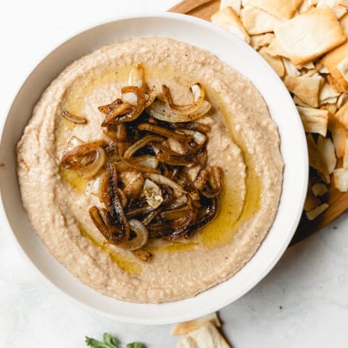 white bean dip topped with caramelized onions served with pita chips