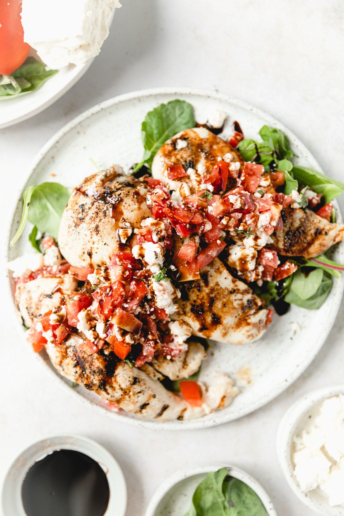 grilled chicken topped with tomato, feta, and basil salad
