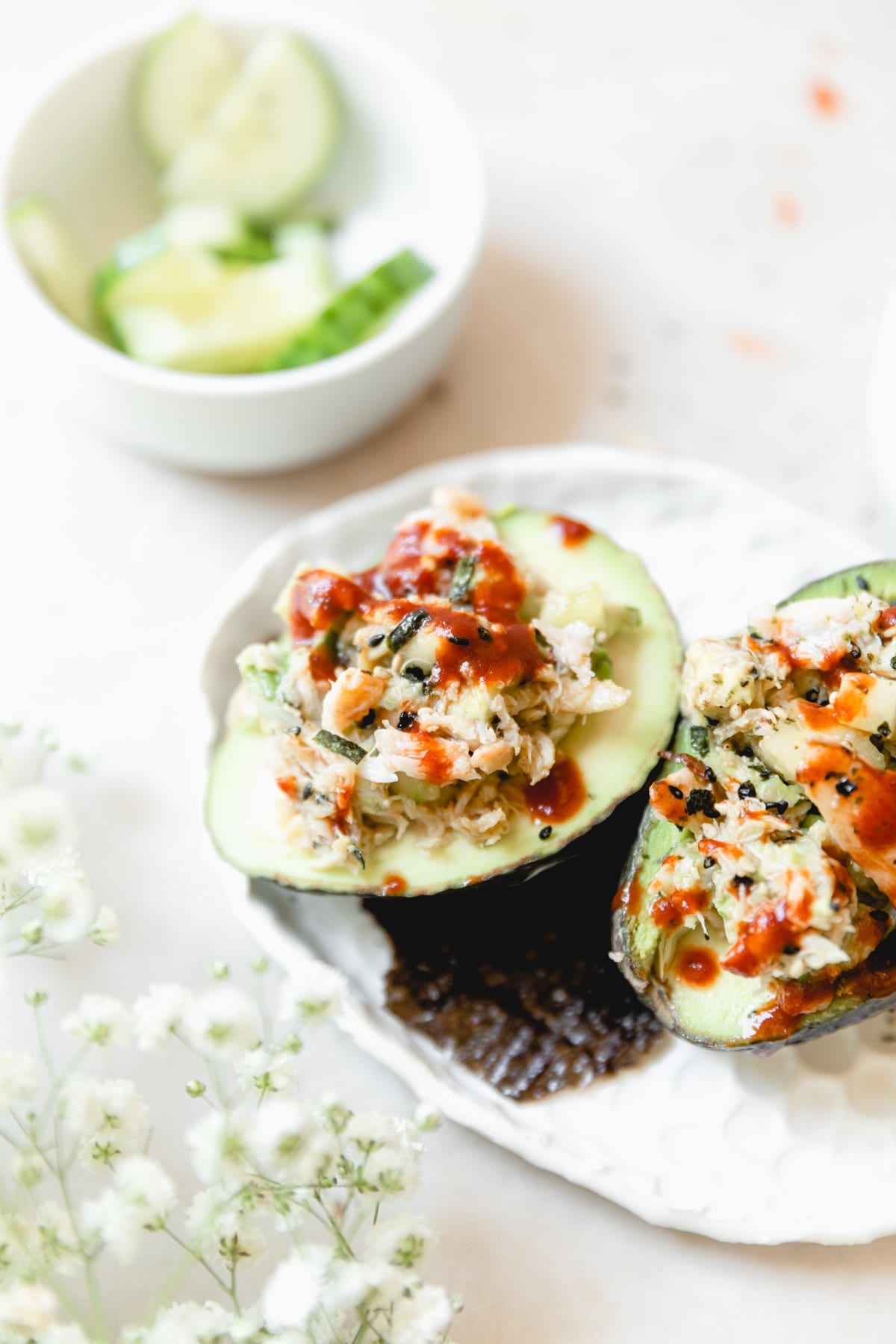 avocado halves stuffed with spicy crab salad and topped with extra sriracha 
