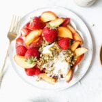 white plate of fruit with burrata cheese and pistachios