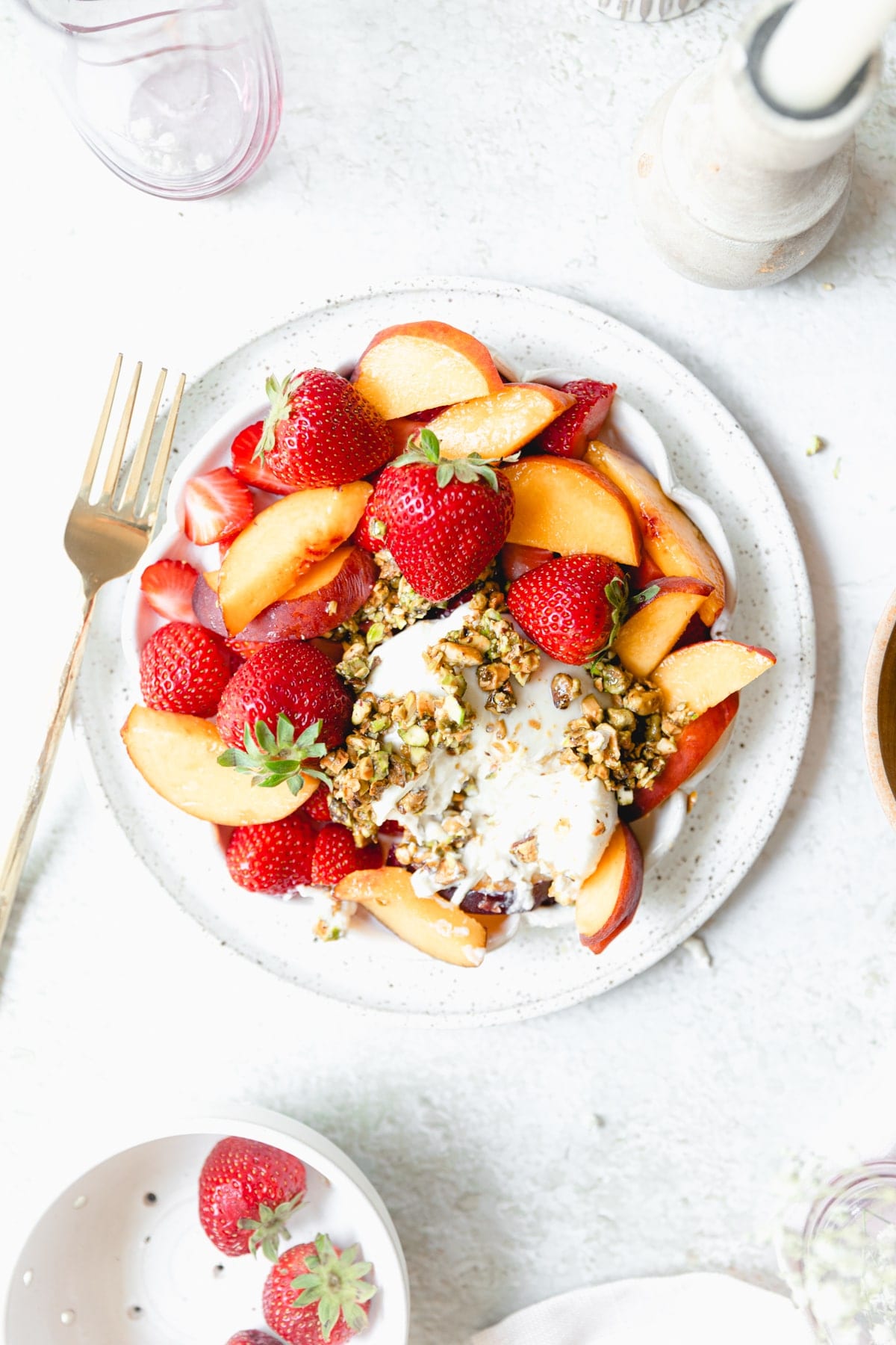 white plate full of strawberries and peaches served with burrata cheese
