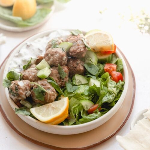 white bowl of meatballs and a side salad