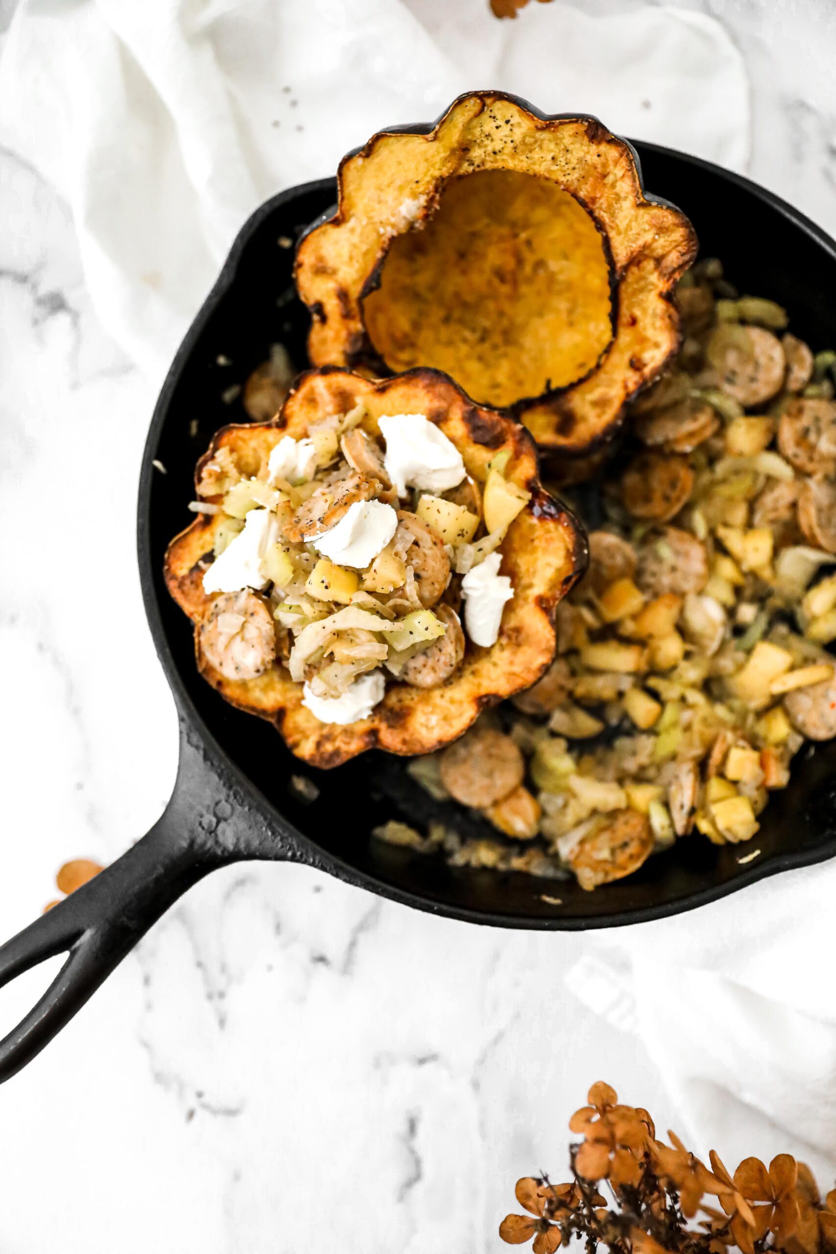 cast iron pan with stuffed acorn squash in it
