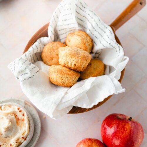 wooden bowl of cornbread muffins lined with a tea towel